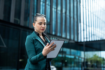 successful young caucasian business woman wear stylish suit hold tablet against the business center