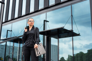 stylish woman in suit with shopping bags  near modern glass building in city. Shopping concept