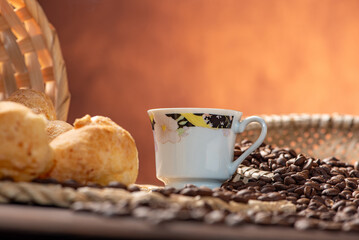 Cheese bread and coffee, delicious Brazilian cheese bread and a beautiful cup of coffee on a rustic table and coffee beans, abstract background, selective focus.