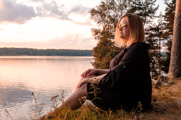 A Contemplative Woman Pondering by the Beautiful Lakeside During a Stunning Sunset