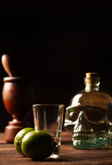 Cachaça from Brazil, bottle of cachaça from Brazil in the shape of a skull, lemon accessories on rustic wood and abstract background, low key photo, selective focus.