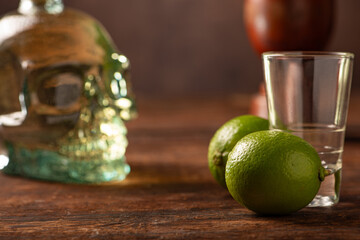 Cachaça from Brazil, bottle of cachaça from Brazil in the shape of a skull, lemon accessories on rustic wood and abstract background, low key photo, selective focus.