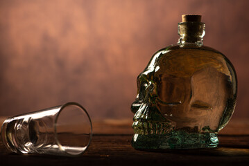 Cachaça, Brazilian cachaça bottle in the shape of a skull and a glass, on rustic wood and abstract background, low key photo, selective focus.