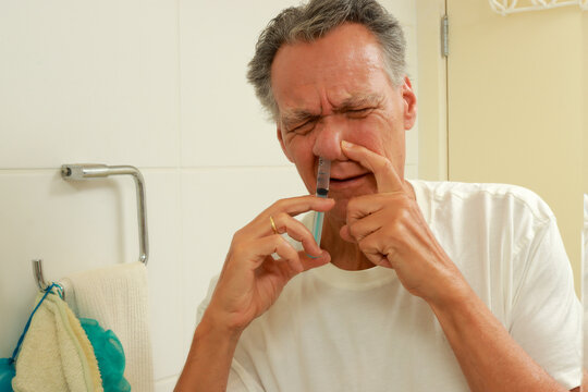 Man using a syringe to cleaning his nose with a salines solution 