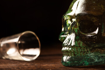 Cachaça, Brazilian cachaça bottle in the shape of a skull and a glass, on rustic wood and abstract background, low key photo, selective focus.