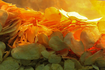 A pile of crispy potato chips, with shades of yellow and golden, is inside a vending cart, with the...