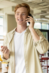 Smiling young man looking excited while talking on the phone
