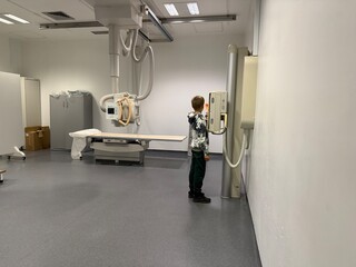Child standing in X-ray room during radiography exam in medical facility