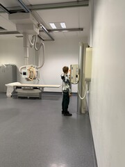 Child standing in X-ray room during radiography exam in medical facility