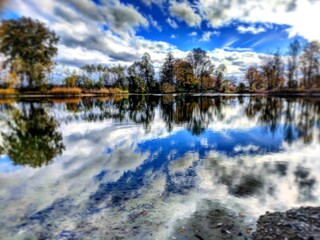 Autumn lake with dramatic sky and cloud reflections on the water surface