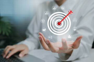 Business target strategy concept. Hand presenting digital dartboard with arrow and marketing strategy icons around the target.