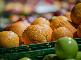 Close-up of oranges and green apples in a plastic crate at a fruit stand