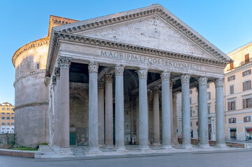Front view of the Pantheon in Rome, an ancient Roman temple with Corinthian columns and a large dome. This iconic ancient structure, completed by Emperor Hadrian around 126 AD under the blue sky.