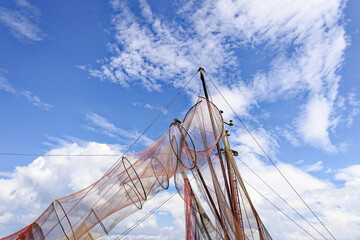 Colorful fishing nets draped over the mast of an old fishing boat, set against a bright blue sky...