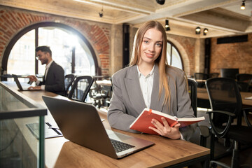 Pretty young woman sitting in the office at the laptop