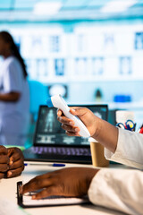 Female doctor measuring the temperature during medical consultation at the cabinet, using a digital...