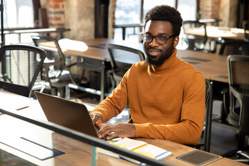 African american young man with laptop working in the office
