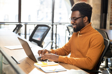 African american young man with laptop working in the office