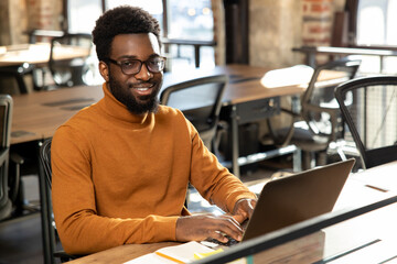African american young man with laptop working in the office