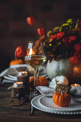 Atmospheric autumn elegant beautiful table setting with pumpkins for a wedding or thanksgiving family celebration. Fall decoration countryside rustic style, cozy home atmosphere , candles, wine