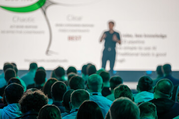 Speaker giving presentation to diverse audience at seminar with large screen in background