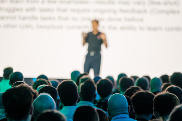 Professional speaker delivers presentation to engaged large audience during a business conference...