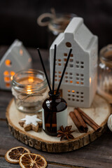 Christmas home aromatherapy. Aroma diffuser with citrus extract, organic essential oil, spruce cone, cinnamon, anise, vanilla scent, aromatic candles, wooden table. Cozy atmosphere, winter inspiration