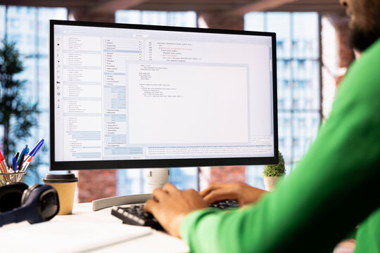Technician in home office looks at UI on computer monitor, typing and executing programming code. Close up shot of IT worker using coding application to write and test code in modern apartment