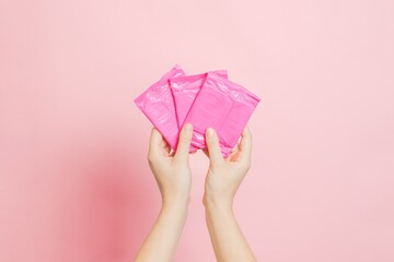 Sanitary pads in hand on pink background. Concept of menstruation, ovulation, reproduction, pain...