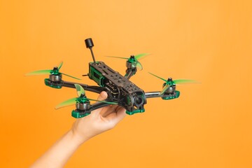 Professional modern drone with camera in hands isolated on orange background