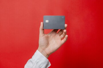 Woman's hand with empty credit card with online service for mockup on red background. Modern way of banking and buying, business, earning