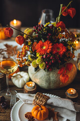 Fall table decoration with pumpkins, wine. Family cozy thanksgiving dinner arrangement indoors at...