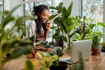 Cute smiling flower shop assistant taking orders by phone