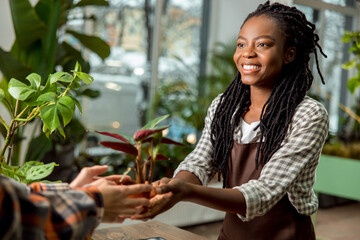 Flower shop assistant selling flower to the customer and smiling nicely