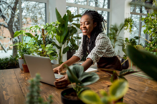 Cute young african american woman at the laptop in the flower shop