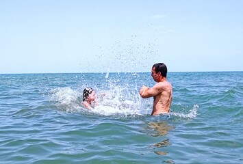 father and daughter are having fun.Girl jumps in to the water . High quality photo