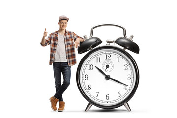 Guy gesturing thumbs up and leaning on a big alarm clock