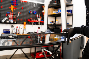 Urethane caulking gun applies flexible adhesive, forming a watertight seal at car windshield replacement. Applying adhesive to a car windshield using a caulking gun.