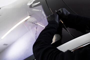 Car windshield replacement process. Windshield removal in progress using specialized cutting wire...