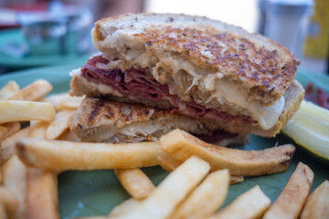 Stacked beef panini sandwich with melted cheese and thick fries served on a blue-green plate
