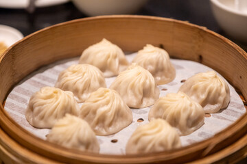 Round bamboo steamer filled with juicy xiao long bao soup dumplings arranged in a circle pattern