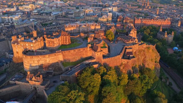 Aerial video of Edinburgh Cityscape touched by the first light of the sunrise featuring the iconic Castle on the rock. 