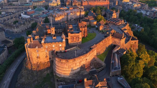 Aerial video of Edinburgh Cityscape touched by the first light of the sunrise featuring the iconic Castle on the rock. 