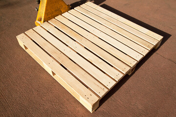 Empty wooden pine pallet with a pallet truck or transpallet in front of a warehouse, logistics and industrial transportation