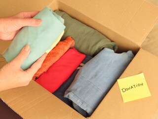 Woman hands preparing a box of clothes for donation. Packing clothes for donation.