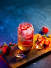 Strawberry lemonade cocktail on a tray on a blue background. Fresh strawberries with soda and ice