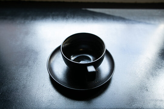 black cup on black windowsill reflecting sunlight