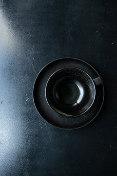 an empty black cup stands on a saucer with crumbs on a black windowsill