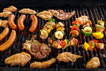 Mixed grill with sausages, vegetables and meat on barbecue