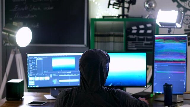 Focused Post-Production Specialist at Multi-Monitor Setup in Dimly Lit Room